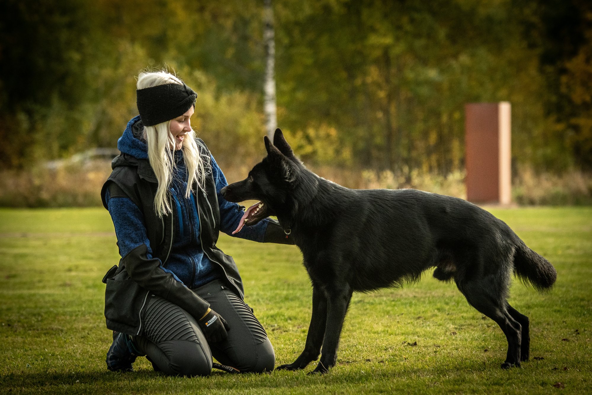 Jenna Tihumäki kneeling with a black German Shepherd